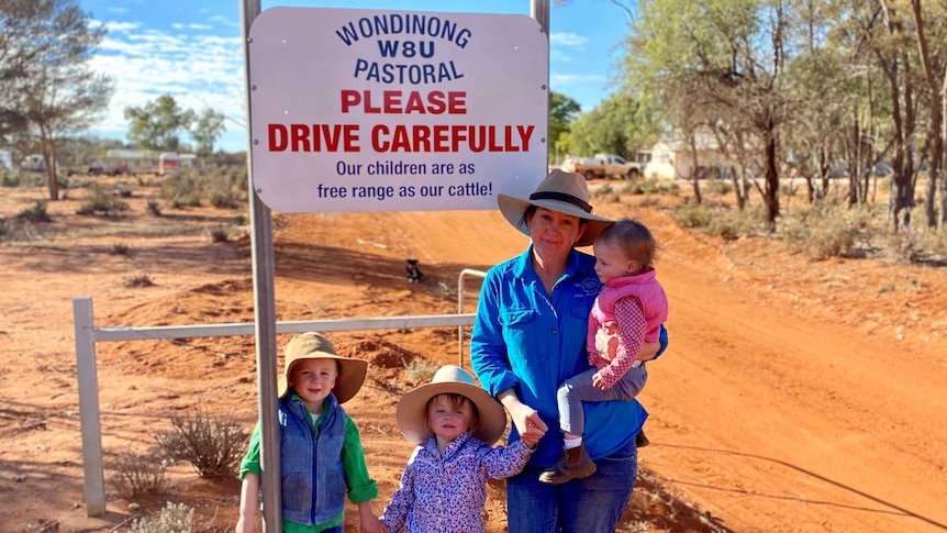 Lara Jensen with her three children in front of a Wondinong Station sign