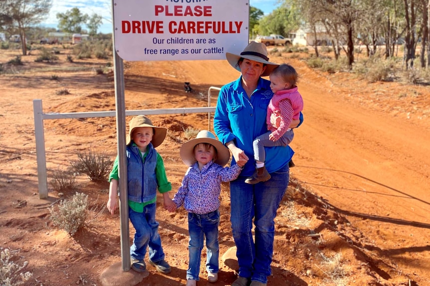 Lara Jensen with her three young children in front of a Wondingong Station sign