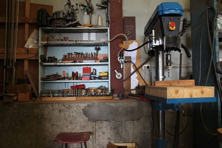 A cabinet with various metal tools and an electronic drill.