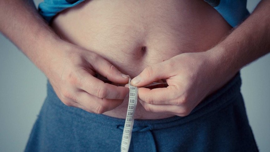 A man measuring his waistline.