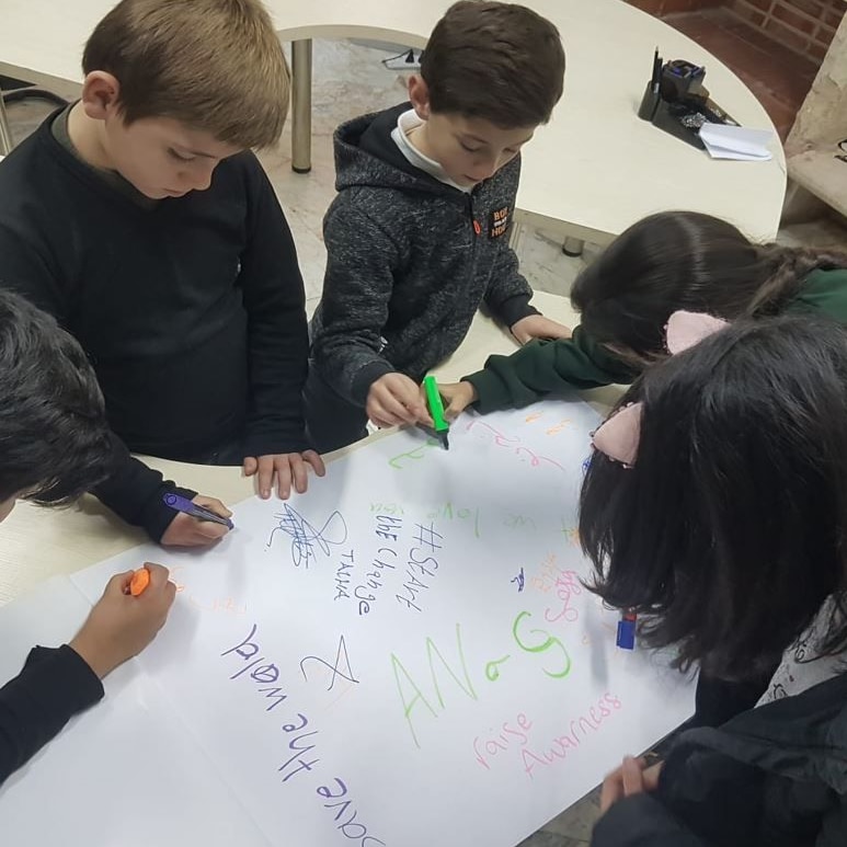 A group of children pictures writing messages on their drawings.