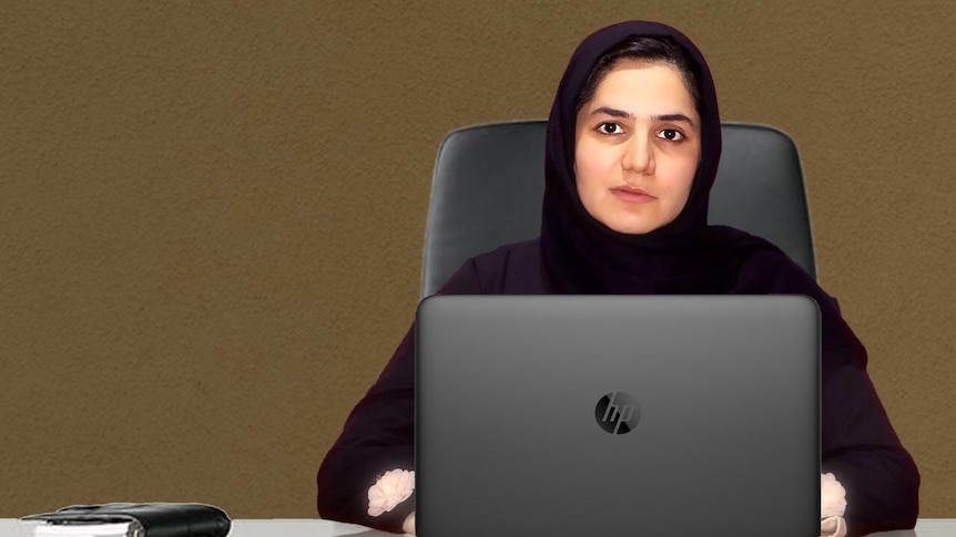 Sodaba Herari sits behind a desk dressed in black using a laptop.