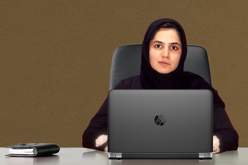 Sodaba Herari sits behind a desk dressed in black using a laptop.