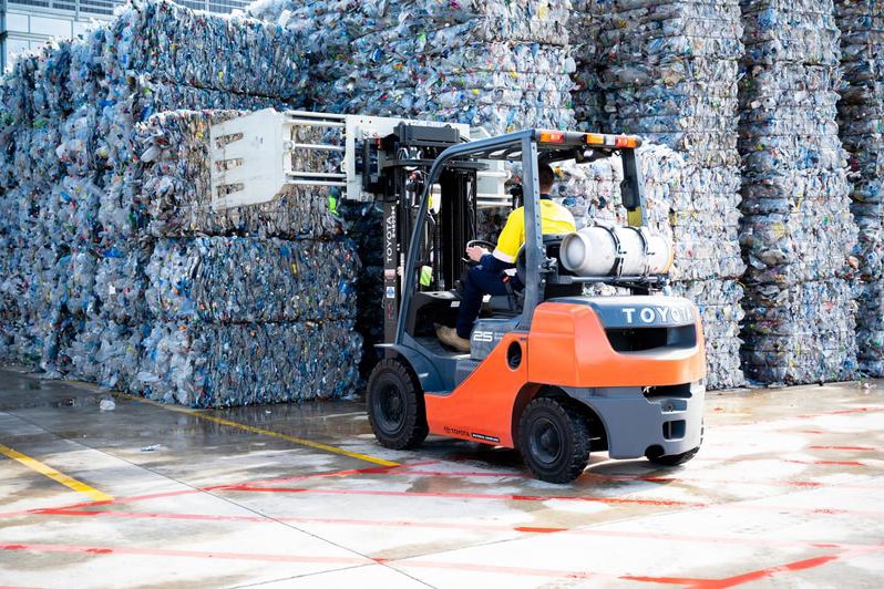 A forklift with a load of crushed plastics inside a factory
