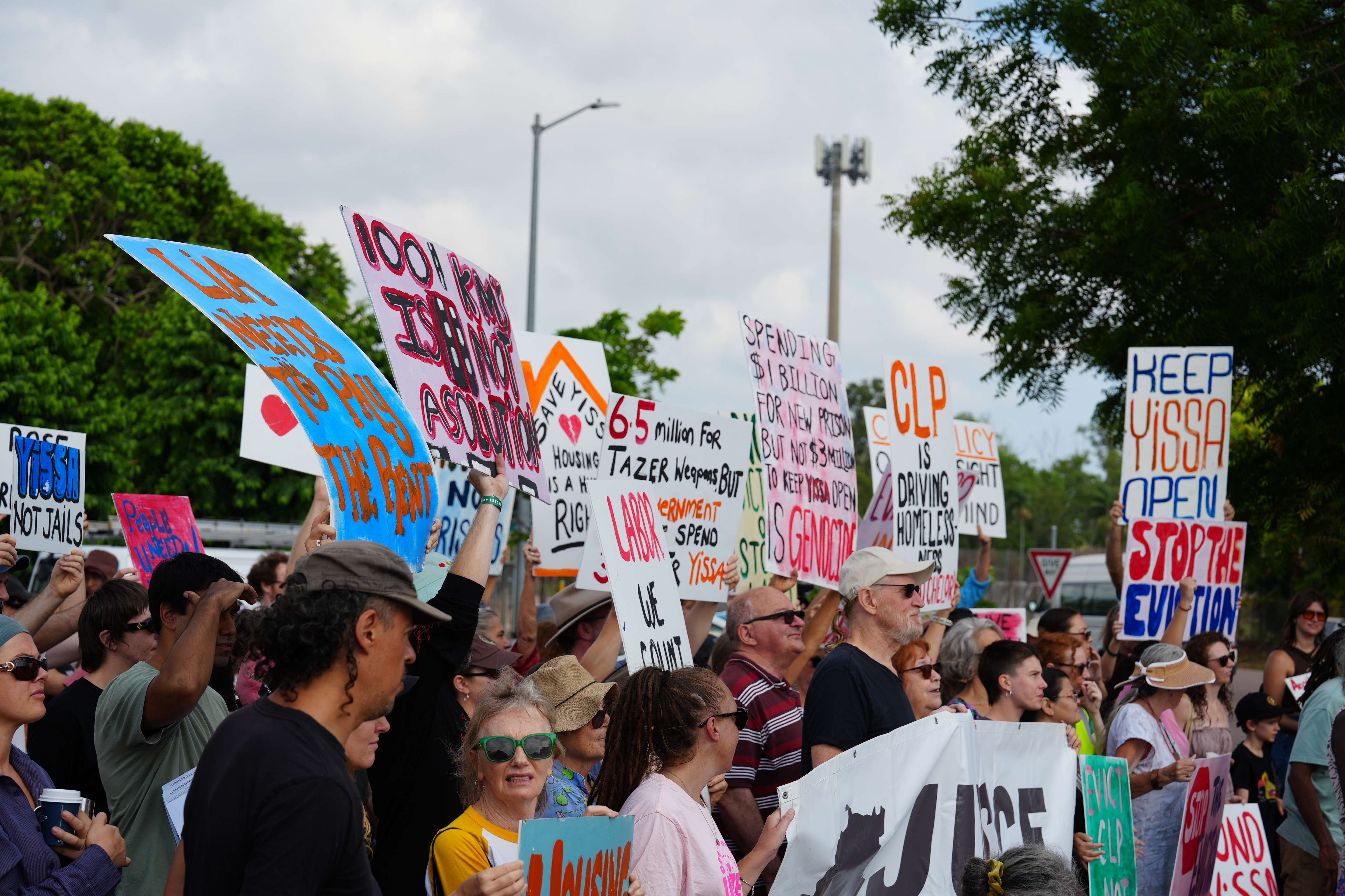 A group of about two dozen protesters holding signs outdoors.