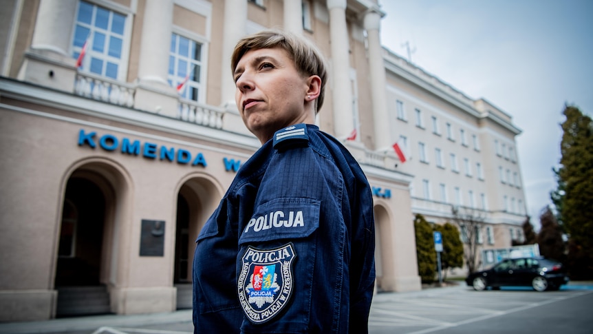 A female police officer stands in a town square looking serious 