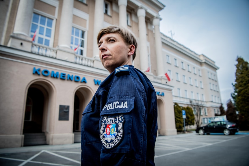 A female police officer stands in a town square looking serious 