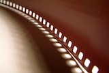 A spool of 35mm film unfurled on a surface