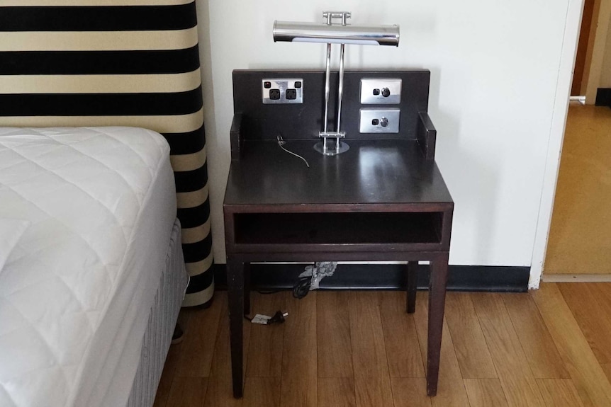 A bedside table next to a bed