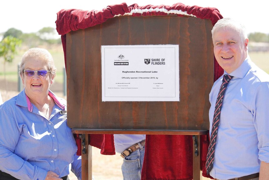 A man and a woman unveil a plaque opening a recreational lake