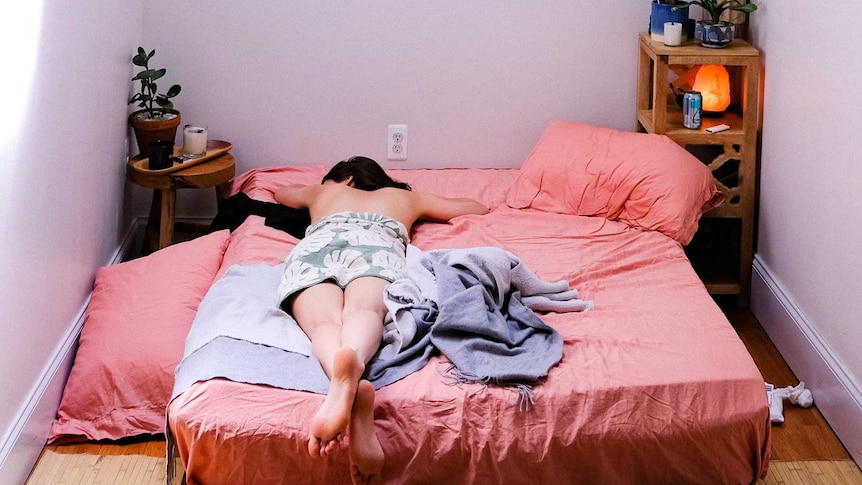 Person lays in unmade bed alone