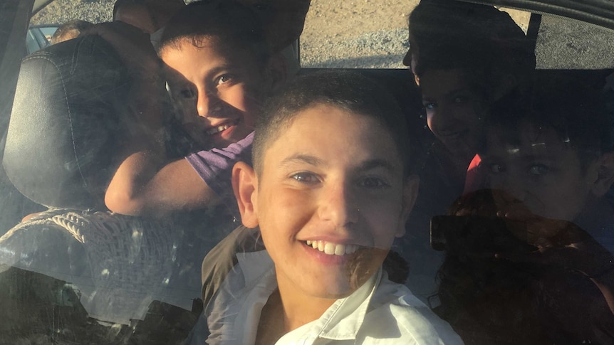 The Ibrahim children smile happily on their journey home.