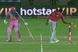 Jos Buttler in pink is out of his crease looking down the pitch, whilst Ravi Ashwin wearing red with 99 on his back turns