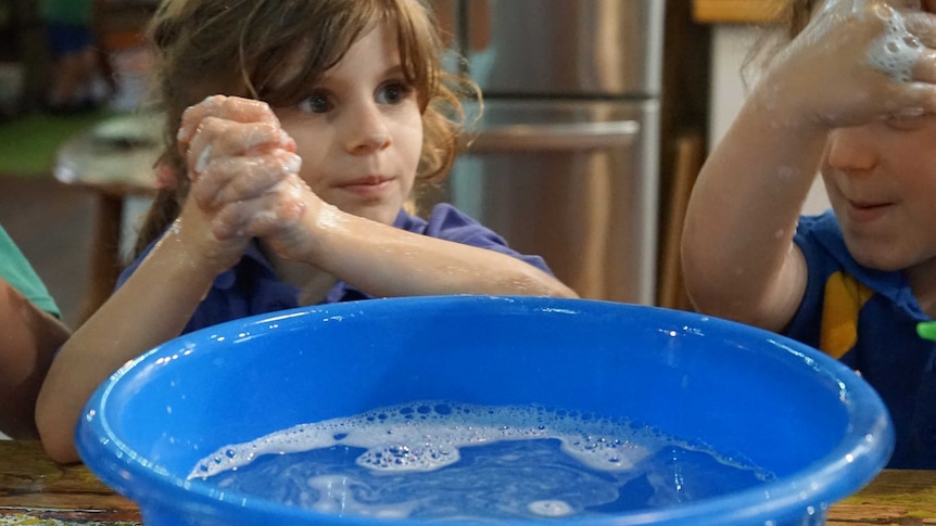 A child washes her hands with soapy water.