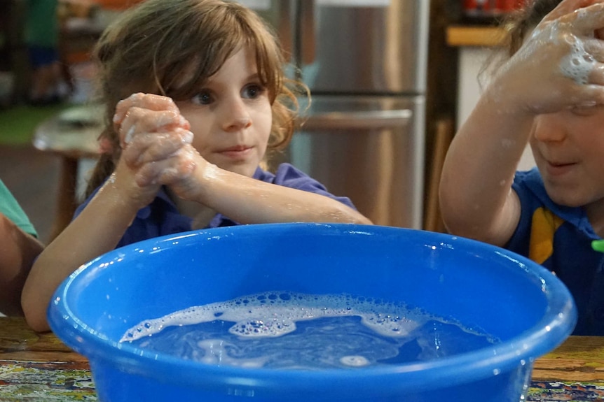 A child washes her hands with soapy water.