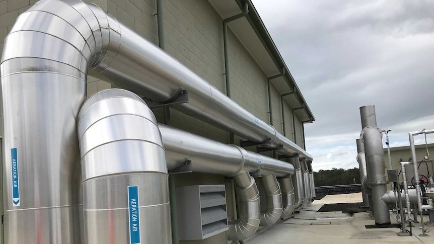 Image of large silver pipe on the side of a wasterwater treatment facility