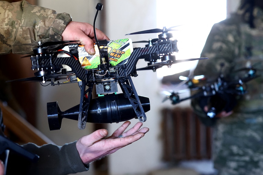A Ukrainian serviceman holds a drone with a grenade.