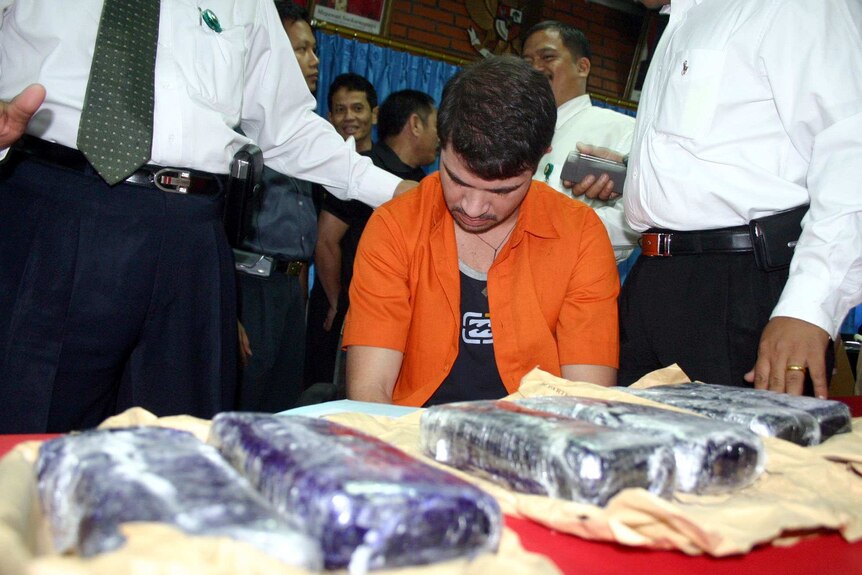 Brazilian drug smuggler Rodrigo Galarte sits at a table with seized six kilograms of cocaine