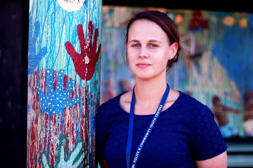 Roebourne PCYC manager Samantha Cornthwaite standing next to a brightly painted pole, wearing a blue top and lanyard.