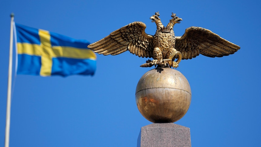 A Russian Imperial double-headed eagle is seen in front of a Sweden flag.
