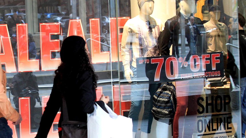 A woman walks past a store displaying sale signs in the Melbourne CBD, June 2012.