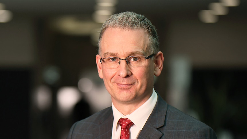 A headshot of Michael Riches, the NT anti-corruption commissioner wearing glasses and a suit with a blurred background