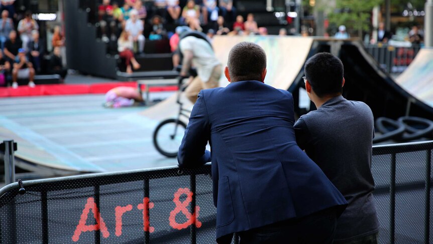 David Lawrence-Watt and Will Curtis stand facing away from the camera watching BMX riders.