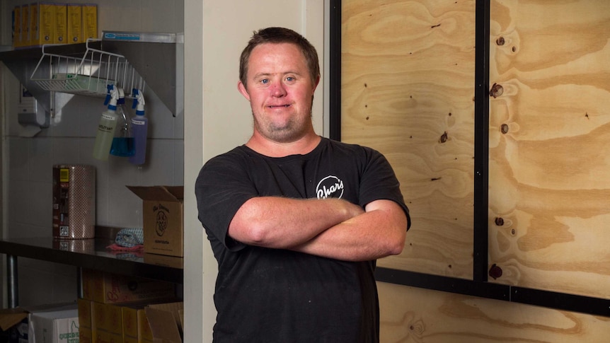 Luke Ward stands arms folded in the café.