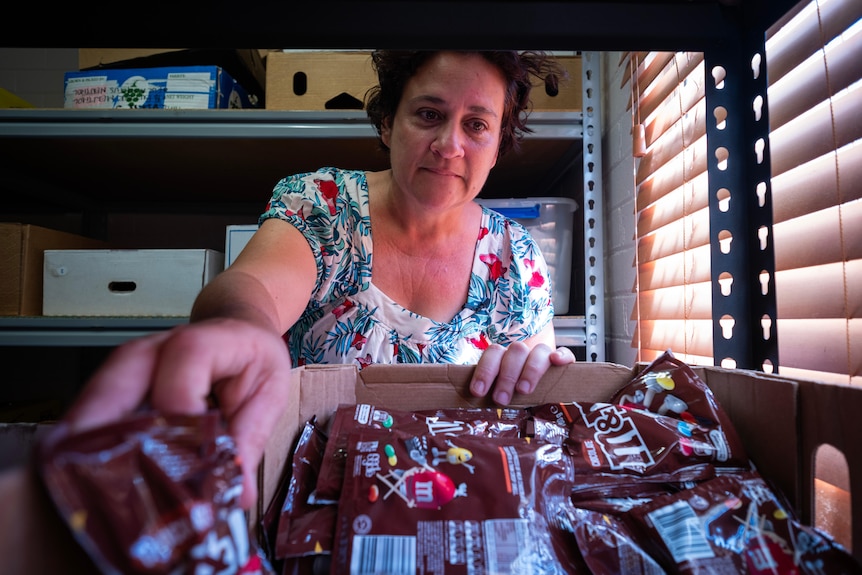 A woman reaches into a box of chocolate packets