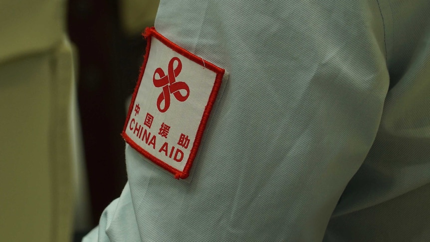 A close up of a an aid workers shirt sleeve that says China Aid in read.