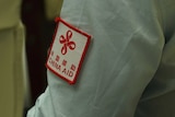 A close up of a an aid workers shirt sleeve that says China Aid in read.