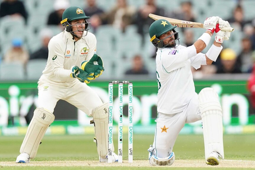 Yasir Shah plays a shot with one knee on the ground as Tim Paine watches on