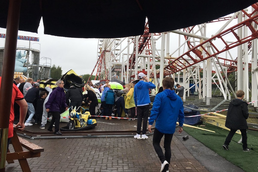 People gather around derailed rollercoaster carriage.
