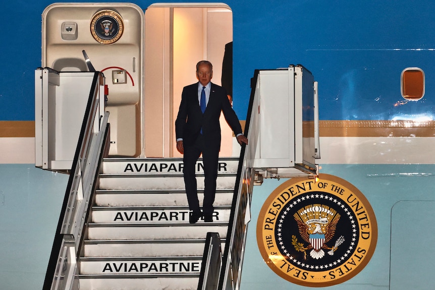 Joe Biden holds the rail as he walks off Air Force One down a set of stairs