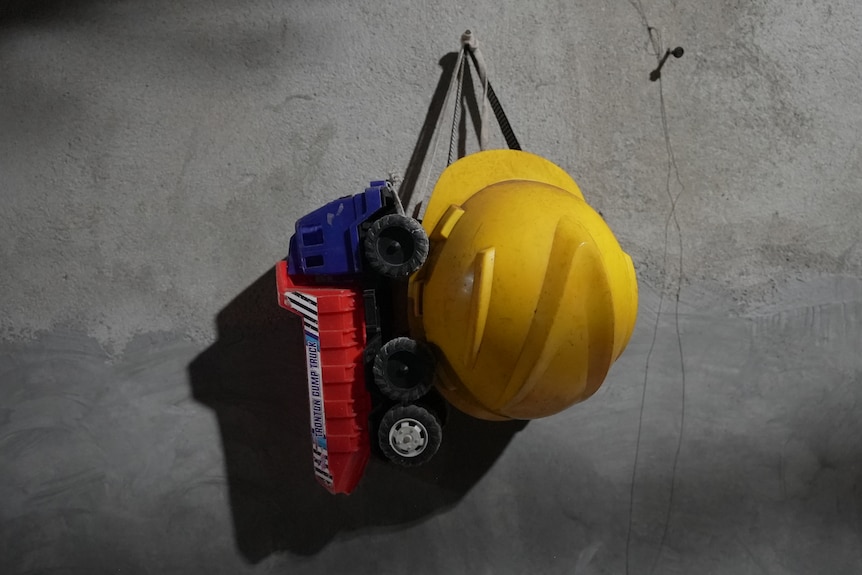 A yellow helmet and a truck toy hanging in the wall.