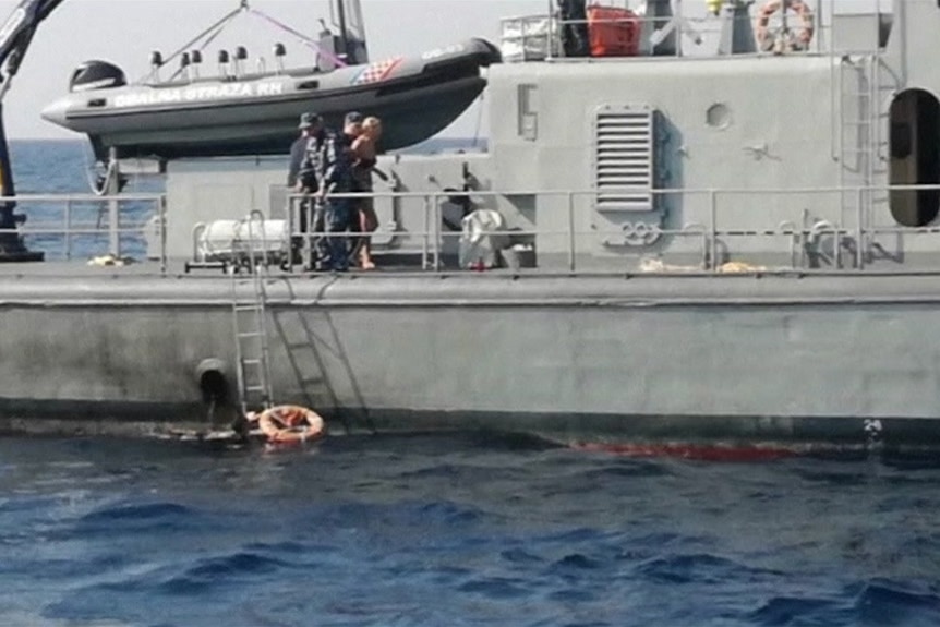 A woman is taken onboard a coast guard boat.