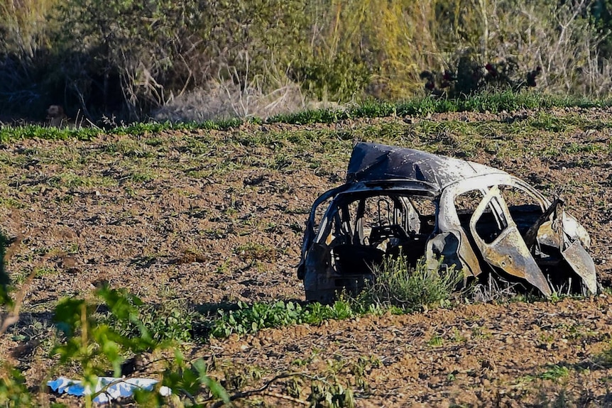 The wreckage of the car of investigative journalist Daphne Caruana Galizia lies next to a road.