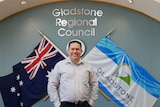 A man with short dark hair - stands in front of a Gladstone Regional Council sign in an office.