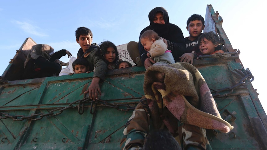A truck full of people are seen with varying sad expressions on their faces as a baby is passed up the back.