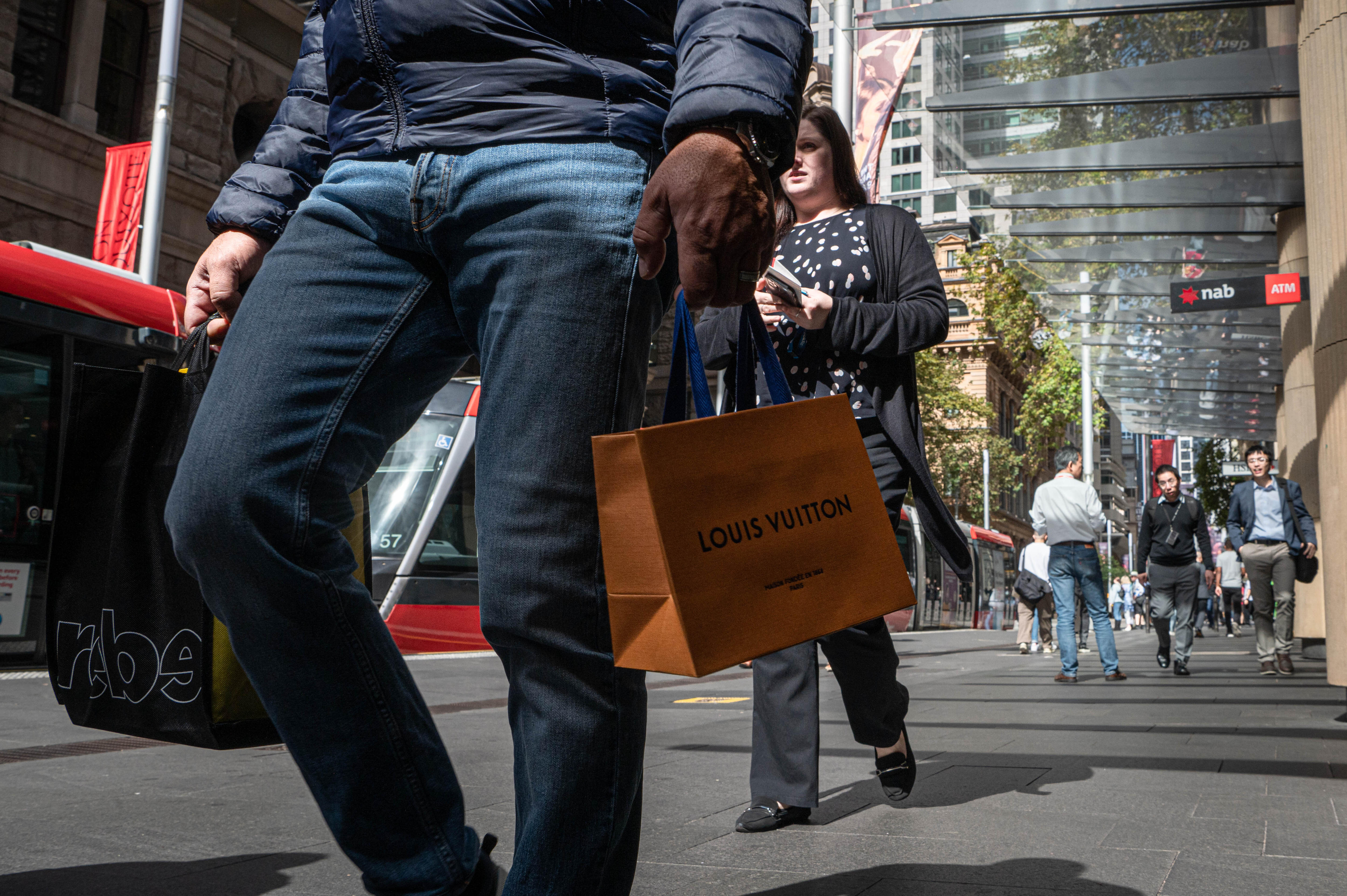 An image of Sydney's CBD, with people walking, faces not visible, carrying shopping bags.