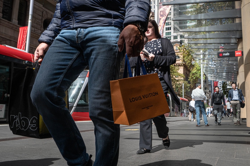 An image of Sydney's CBD, with people walking, faces not visible, carrying shopping bags.