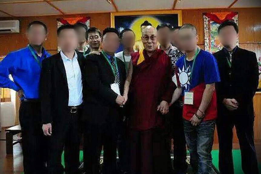 A group of men pose for a photo. Everyone's faces are blurred except two