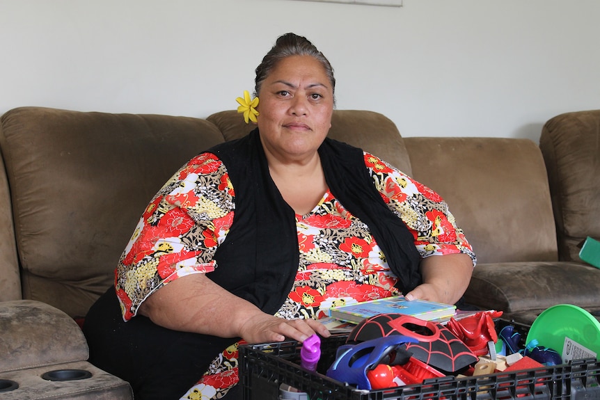 A woman sits on a couch posing for a photo.