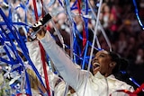 US gymnast Simone Biles holds up her phone and smiles as streamers fall at the national Olympic trials.