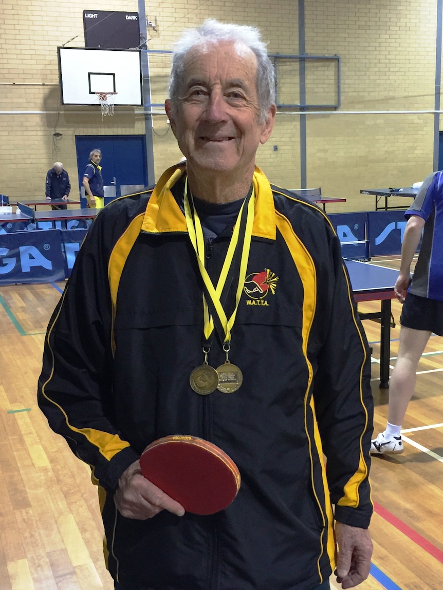 Gordon Lee wearing a black and gold sports jacket with medals around his neck