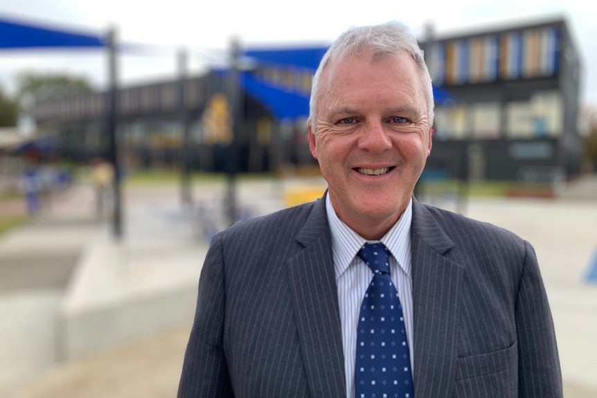 A portrait of Bruce Simons wearing a suit and tie and smiling.