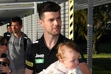Richmond's Trent Cotchin carries a baby as another children walks with him at the AFL's hub on the Gold Coast in Queensland.