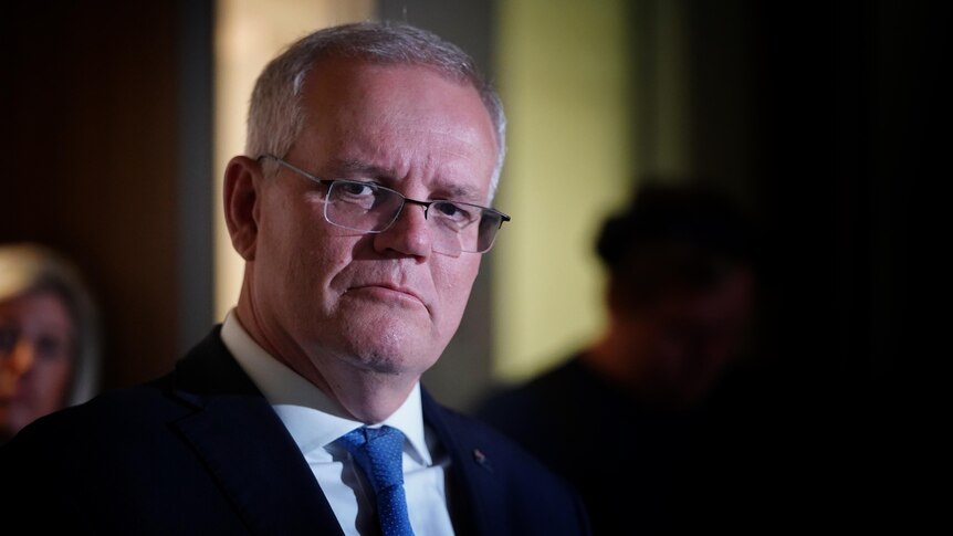 Morrison looks serious as his face is lit up in a dark room.