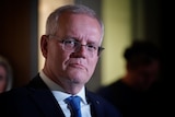 Morrison looks serious as his face is lit up in a dark room.
