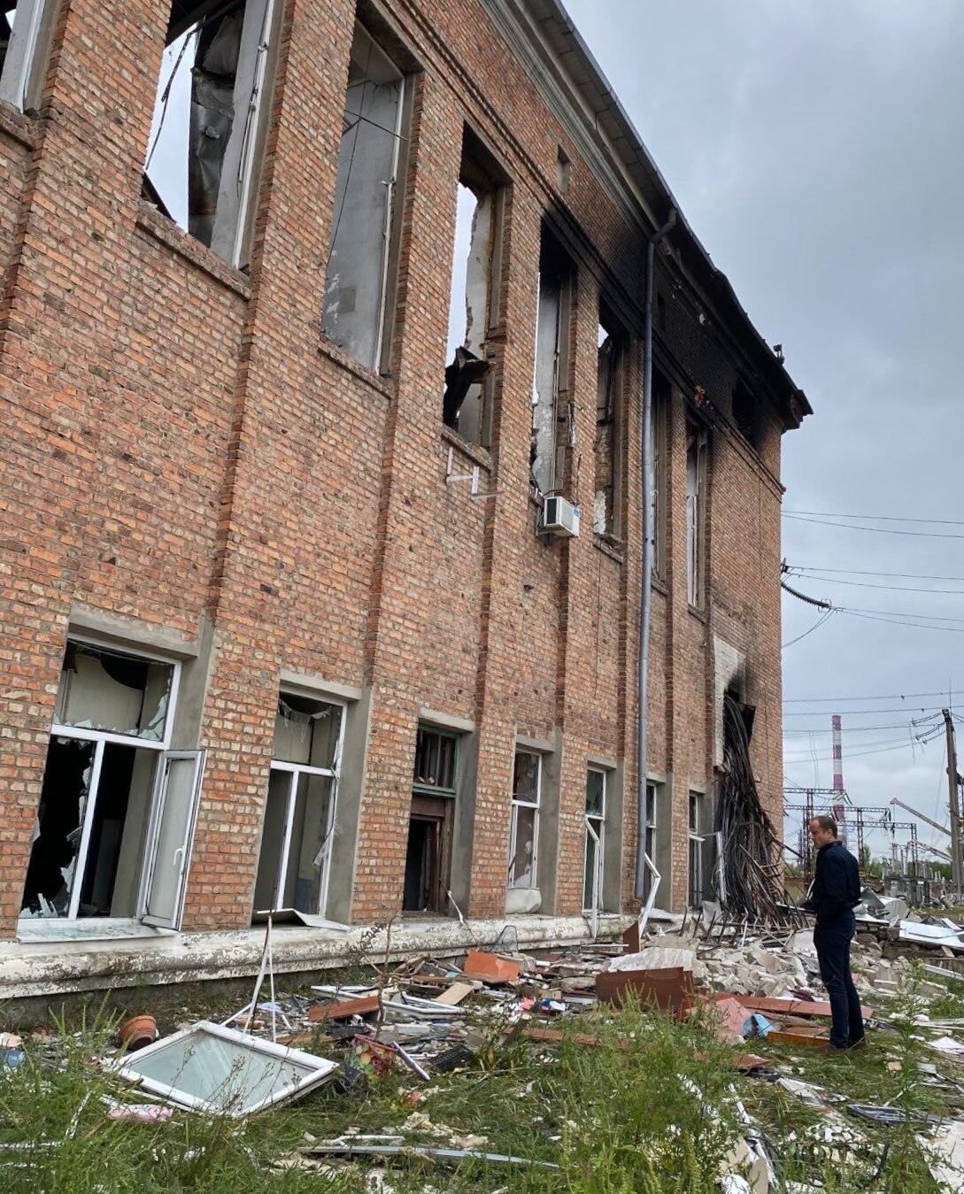 Investigator Nigel Pavoas looks at a charred building with debris strewn on the ground. 
